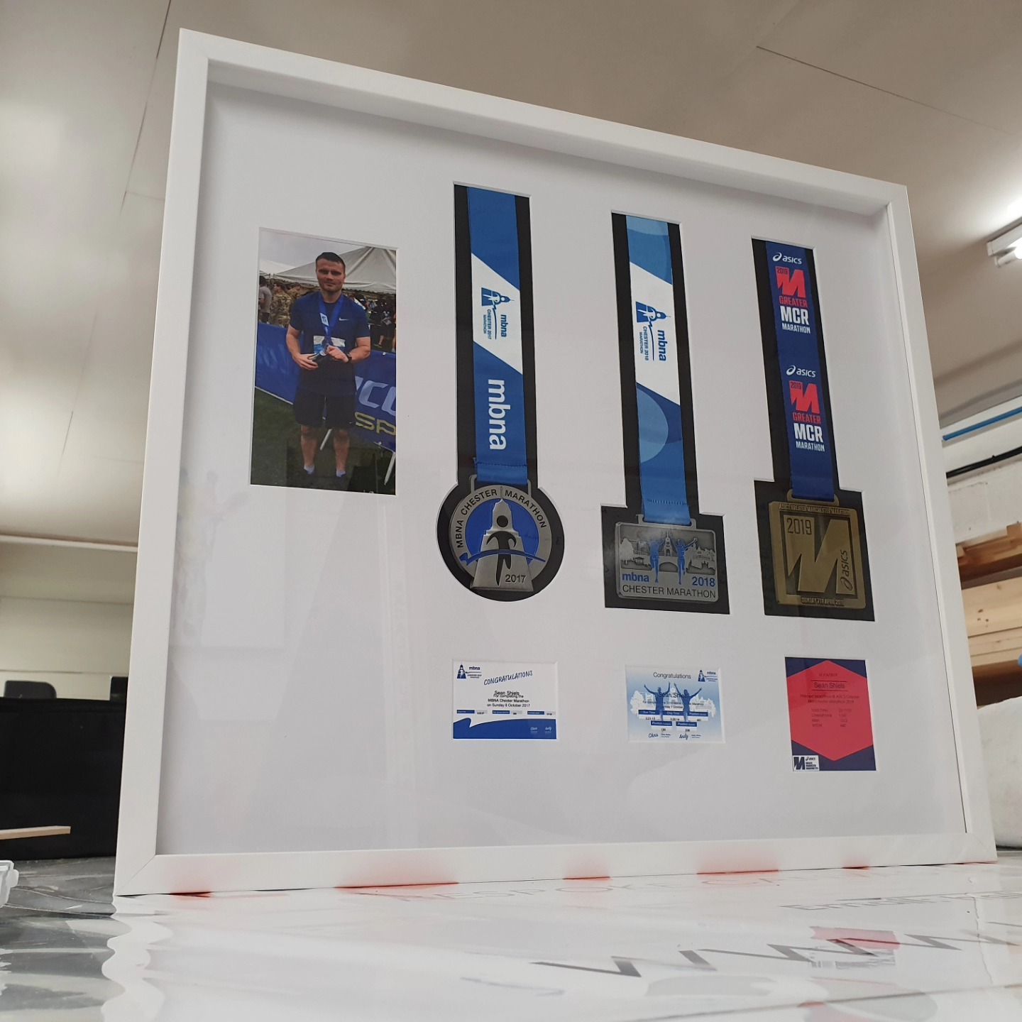 A box-framed marathon medal display behind UV-protective glass at Love to Frame